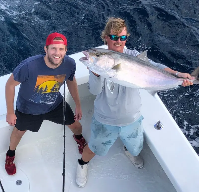 Two men holding a fish on the boat