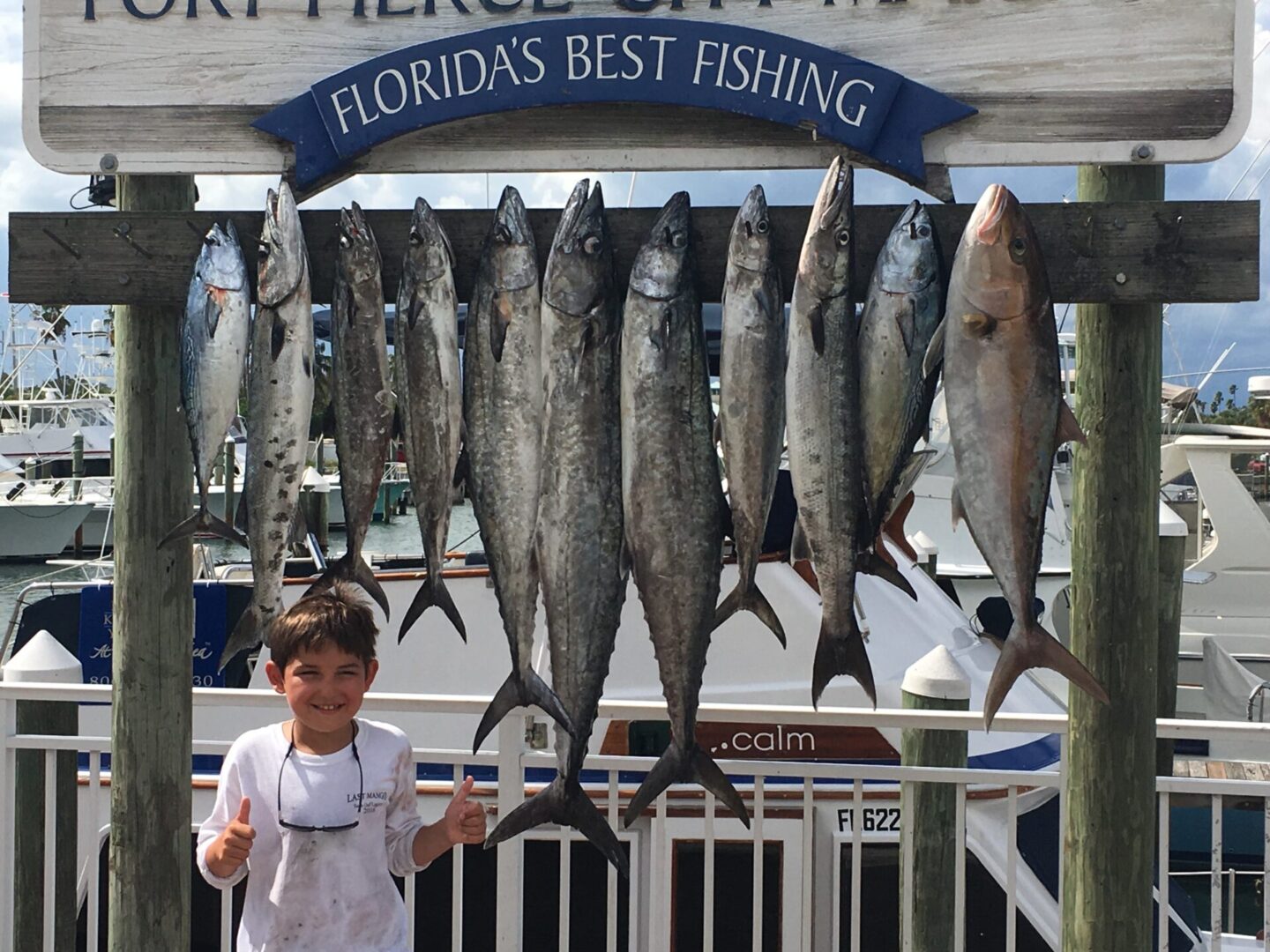 A boy standing next to a bunch of fish.