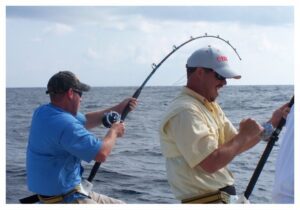 Two men fishing in the ocean while one of them is holding a rod.