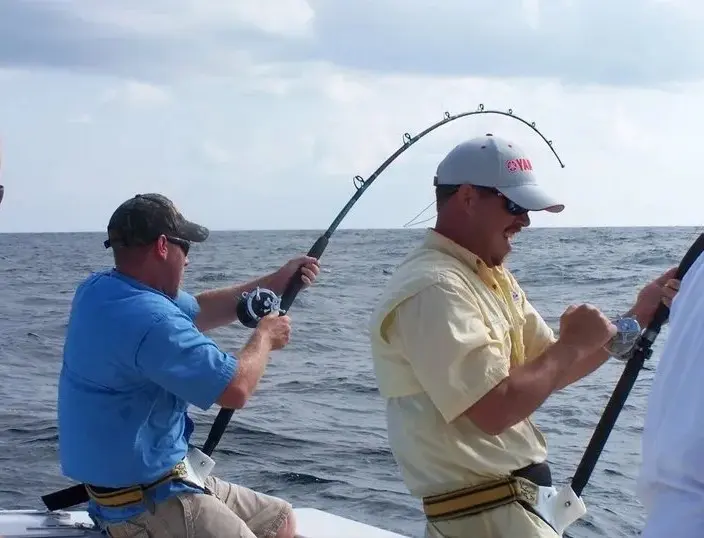 Two men fishing on a boat in the ocean.